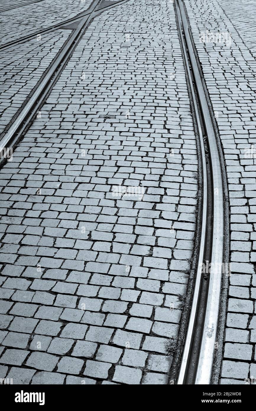 Binari e piastrelle del tram formano un disegno grafico sulle pietre da pavimentazione a Porto, Portogallo Foto Stock