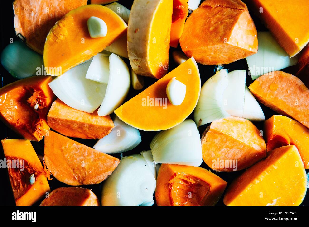 Verdure a pezzi su vassoio di arrostimento. Zuppa di zucca di butternut arrosto pronta per essere portata in forno. Preparazione di zuppe fatte in casa. Dieta sana Foto Stock