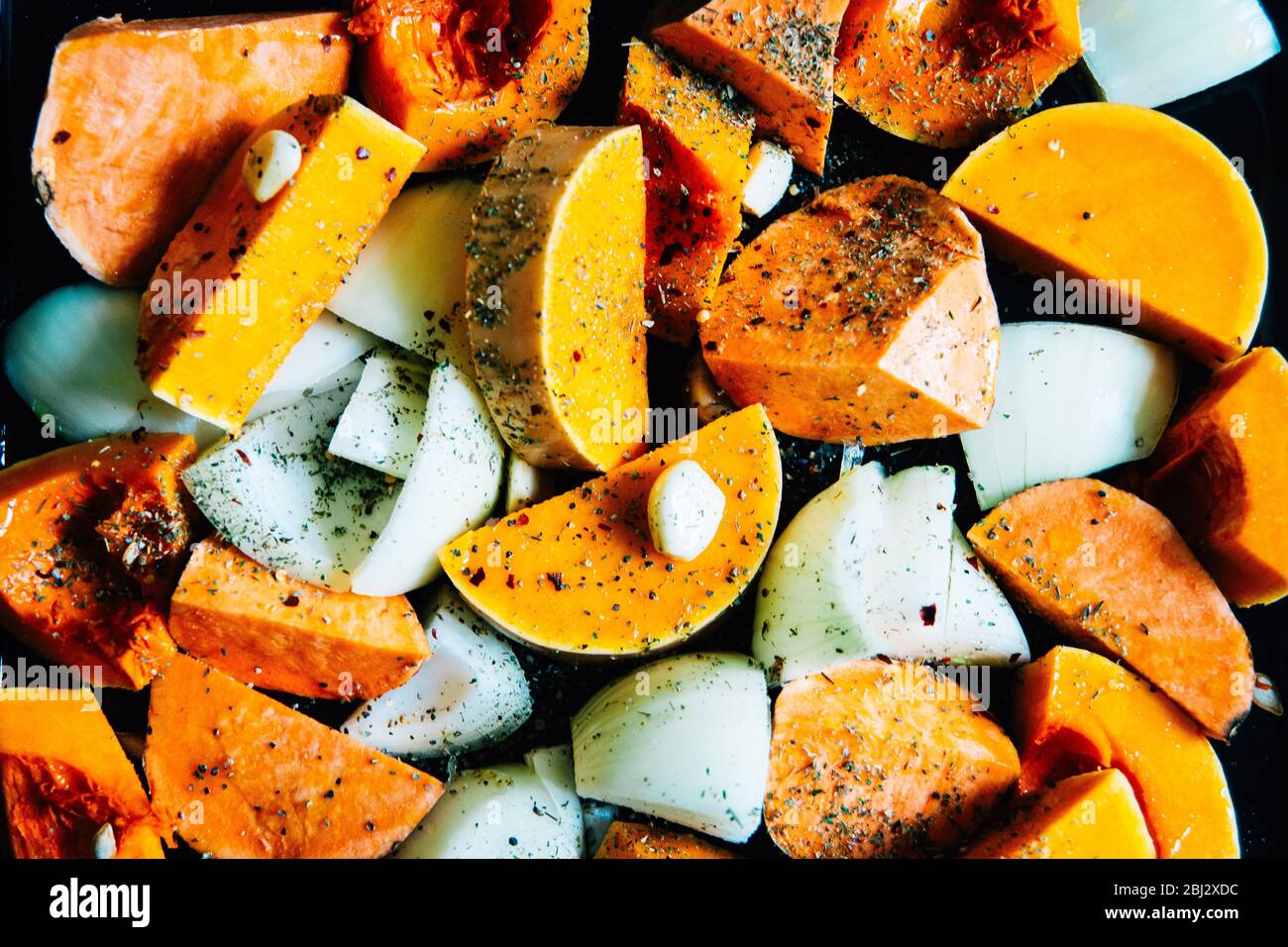 Verdure a pezzi su vassoio di arrostimento. Zuppa di zucca di butternut arrosto pronta per essere portata in forno. Preparazione di zuppe fatte in casa. Dieta sana Foto Stock