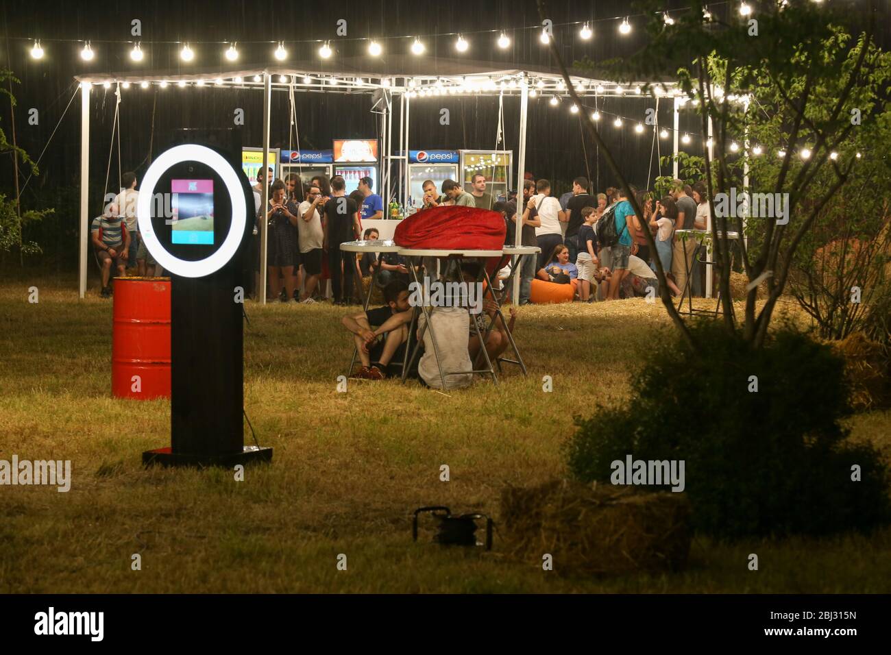 Udienza con le mani sollevate a un festival di musica e luci streaming verso il basso a partire da sopra il palcoscenico. Soft focus, ISO elevata, immagini sgranate. Foto Stock