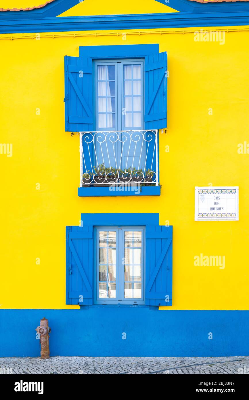 Facciata blu e gialla dai colori vivaci, balconi, persiane, idrante a Cais dos Botiroes presso il porto turistico di Aveiro, Portogallo Foto Stock