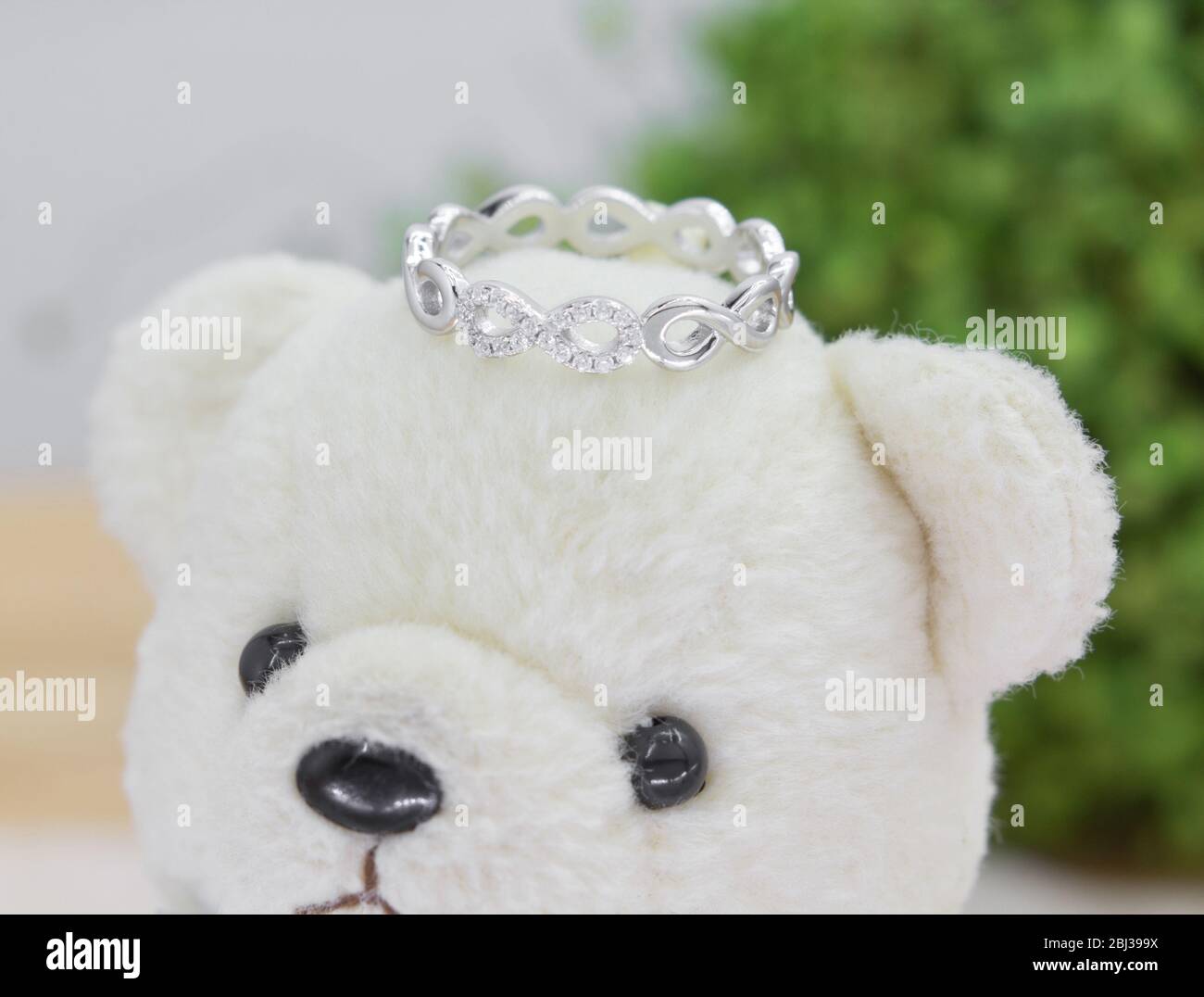 bellissimo anello in argento a forma di infinità decorato con diamanti esposti sull'orso giocattolo Foto Stock