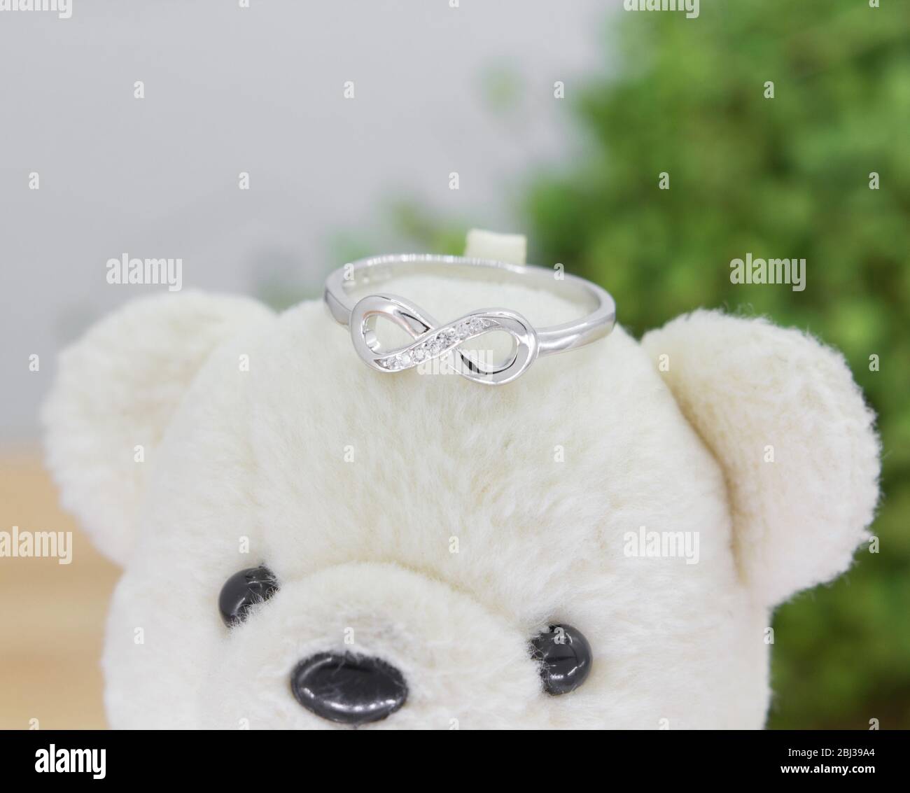 bellissimo anello in argento a forma di infinità decorato con diamanti esposti sull'orso giocattolo Foto Stock