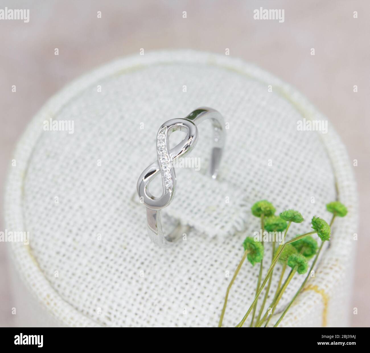 splendido anello in argento a forma di infinità decorato con diamanti sul supporto Foto Stock