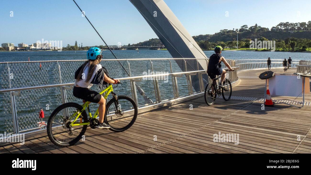 Gli adolescenti che cavalcano le loro bici sopra il Ponte Elizabeth Quay un ponte pedonale a Elizabeth Quay Perth che si affaccia sul Fiume Swan, Australia Occidentale. Foto Stock