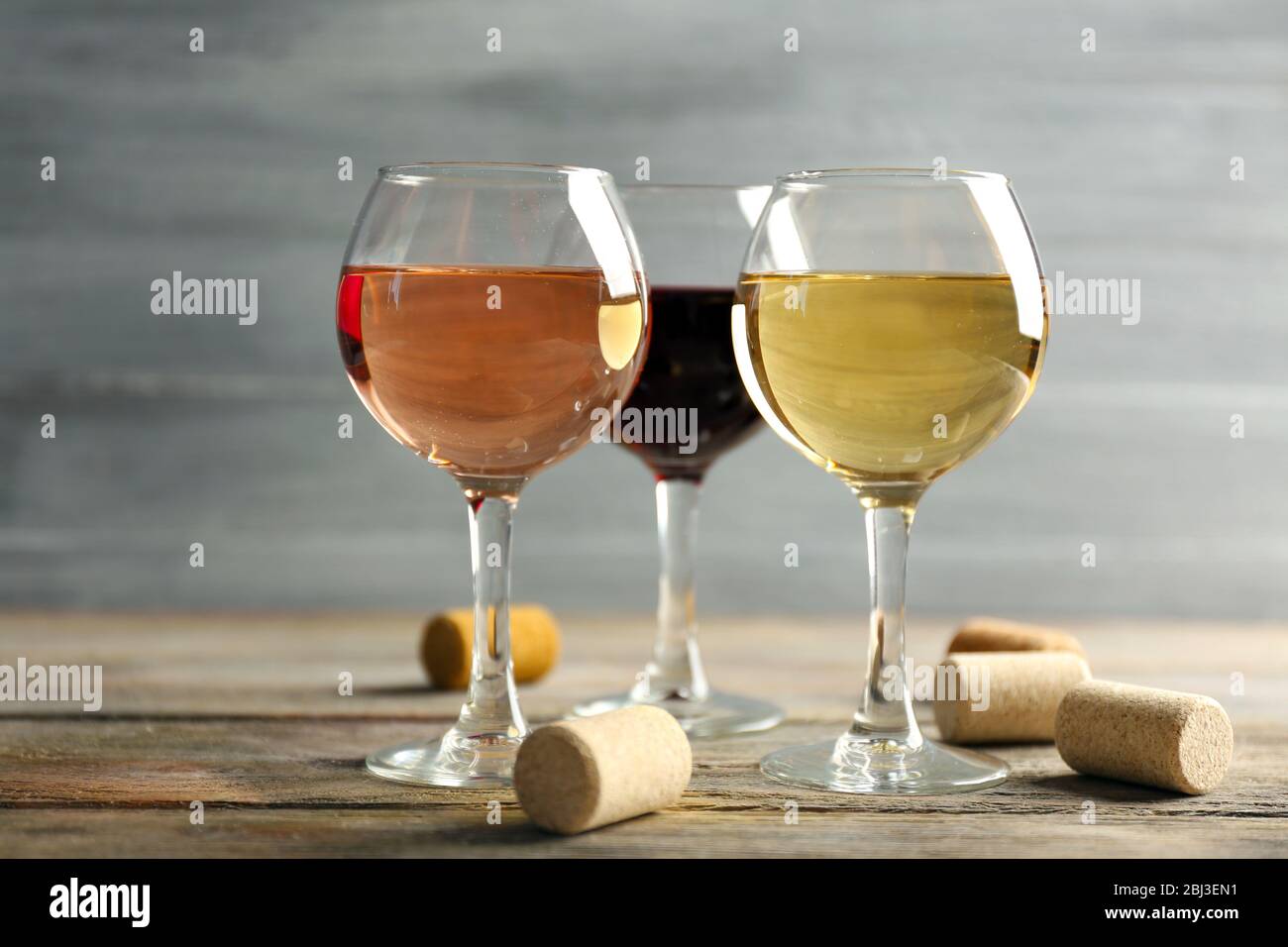 Composizione di bicchieri da vino e tappi su tavolo di legno su sfondo grigio Foto Stock