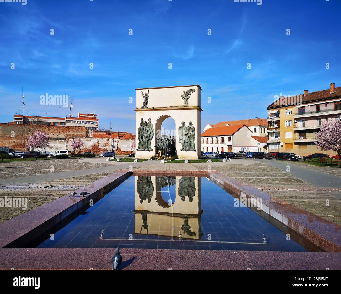 Vista panoramica con monumento ad arco riflesso nella fontana d'acqua in una piazza della città, eatern euro architettura punto di riferimento in Arad, Romania, preso il 03 / Foto Stock
