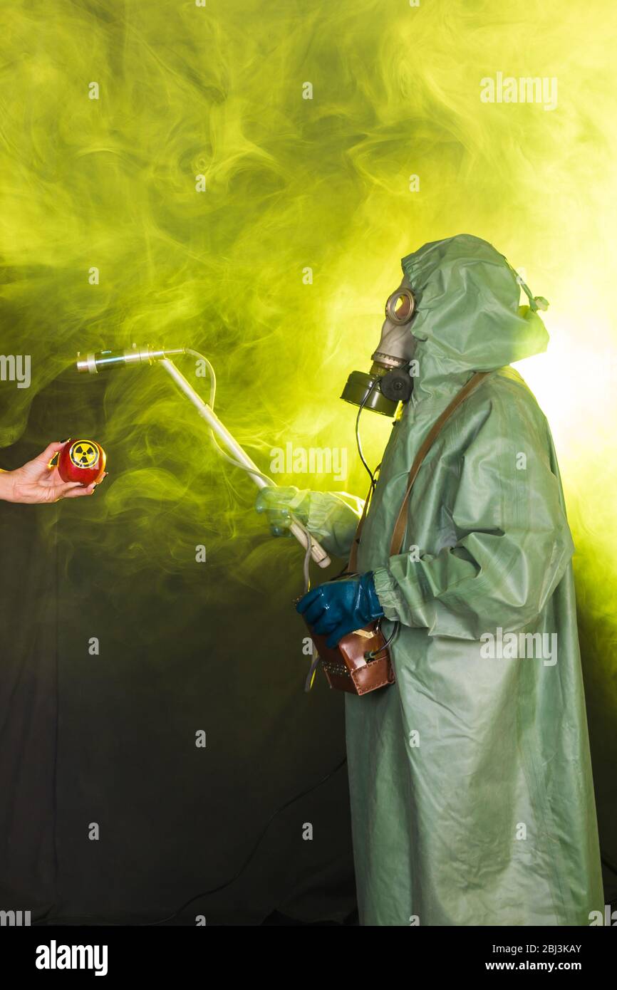 Concetto di radiazione, inquinamento e pericolo - uomo in abbigliamento protettivo e maschera a gas su sfondo scuro Foto Stock