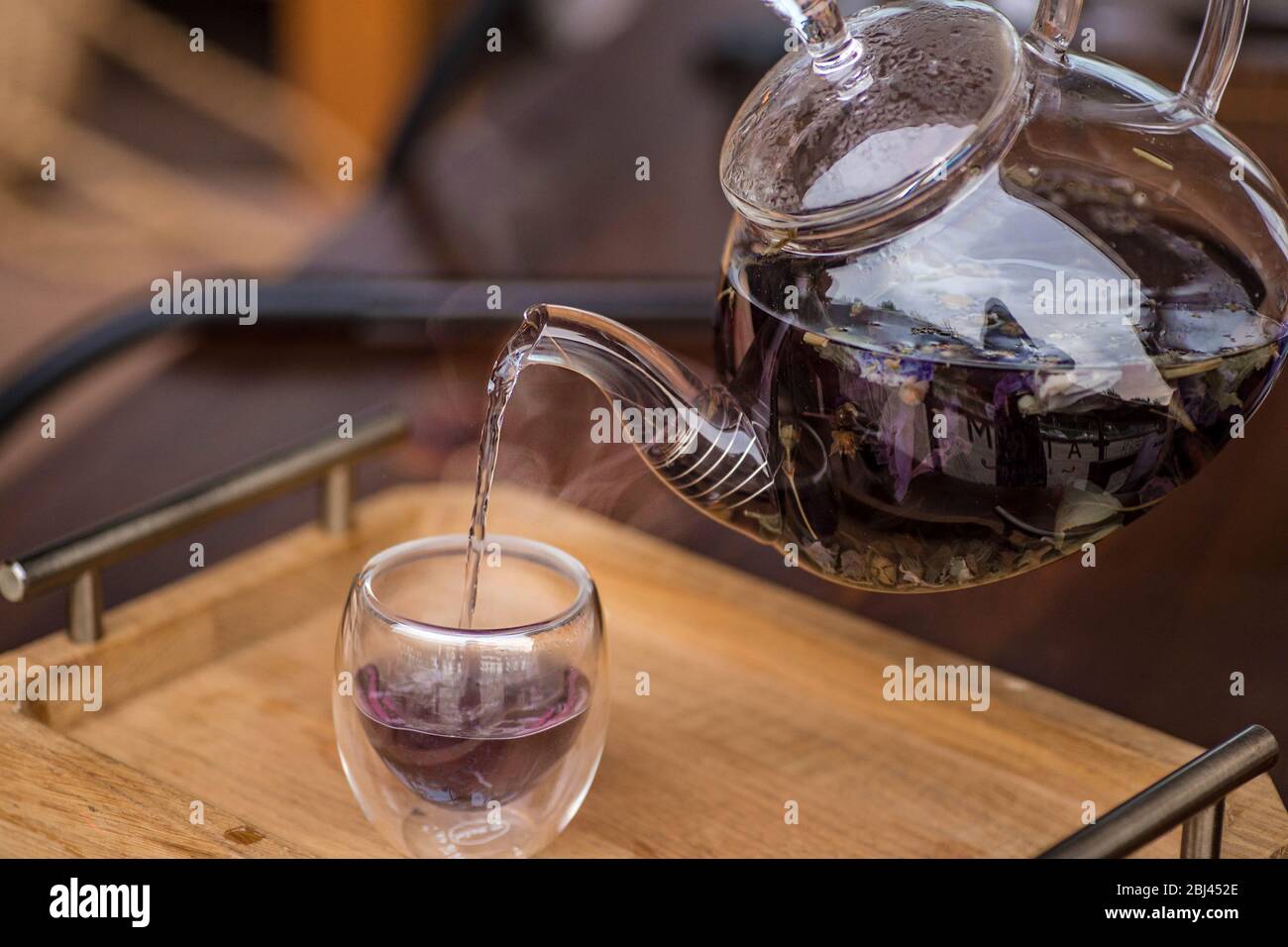 Il tè alle erbe floreale viola viene versato dal produttore nella tazza. Foto Stock