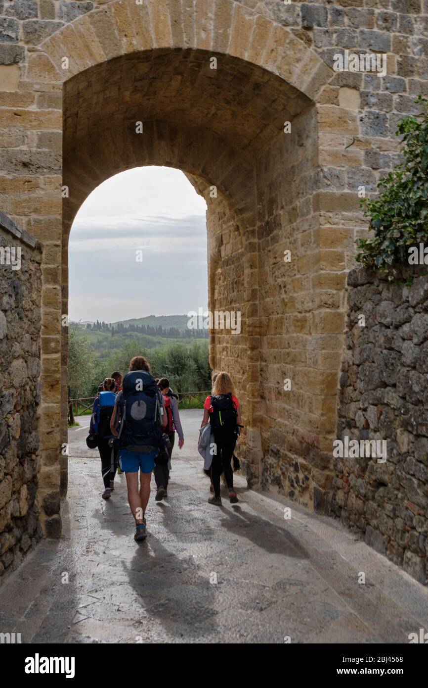 I pellegrini escono da Monteriggioni la mattina presto. Trekking con Backpacker solo sulla Via Francigena da Lucca a Siena. Camminando tra la natura, il suo Foto Stock