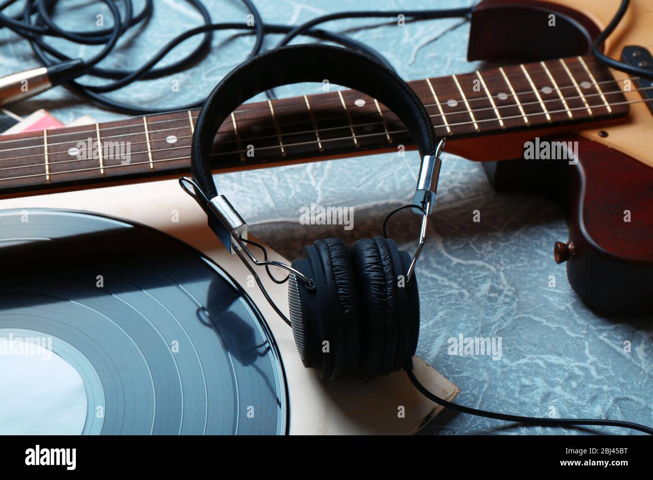 Chitarra elettrica e cuffie con accessori musicali su sfondo grigio Foto Stock