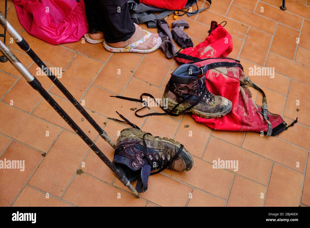 Attrezzatura da trekking umida e fangosa dopo una giornata di passeggiate sotto la pioggia. Trekking con Backpacker solo sulla Via Francigena da Lucca a Siena. Passeggiata tra le due Foto Stock
