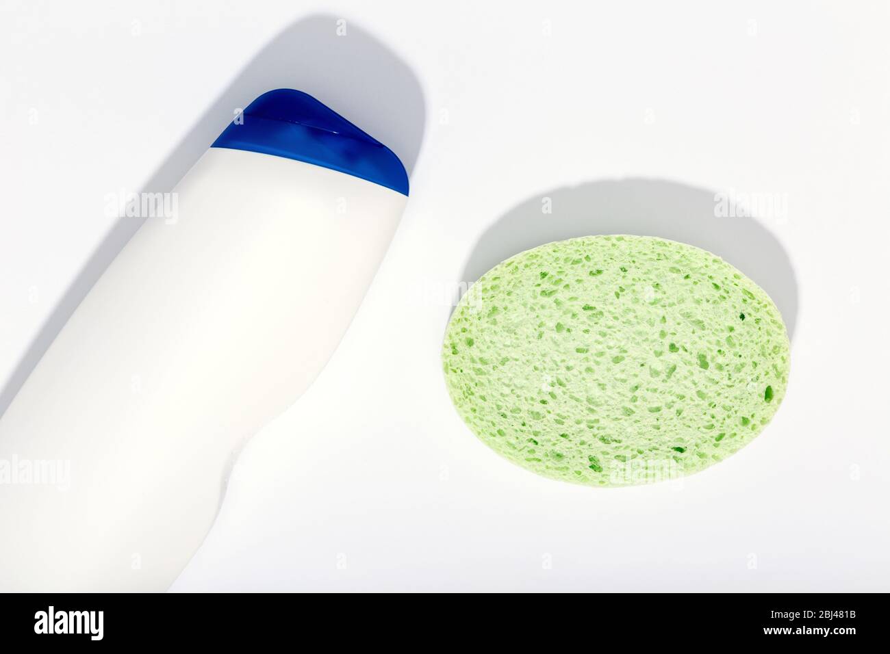 Bottiglia di sapone e spugna in plastica su fondo bianco. Concetto di prodotti per la cura del corpo. Vista superiore Mock up Foto Stock