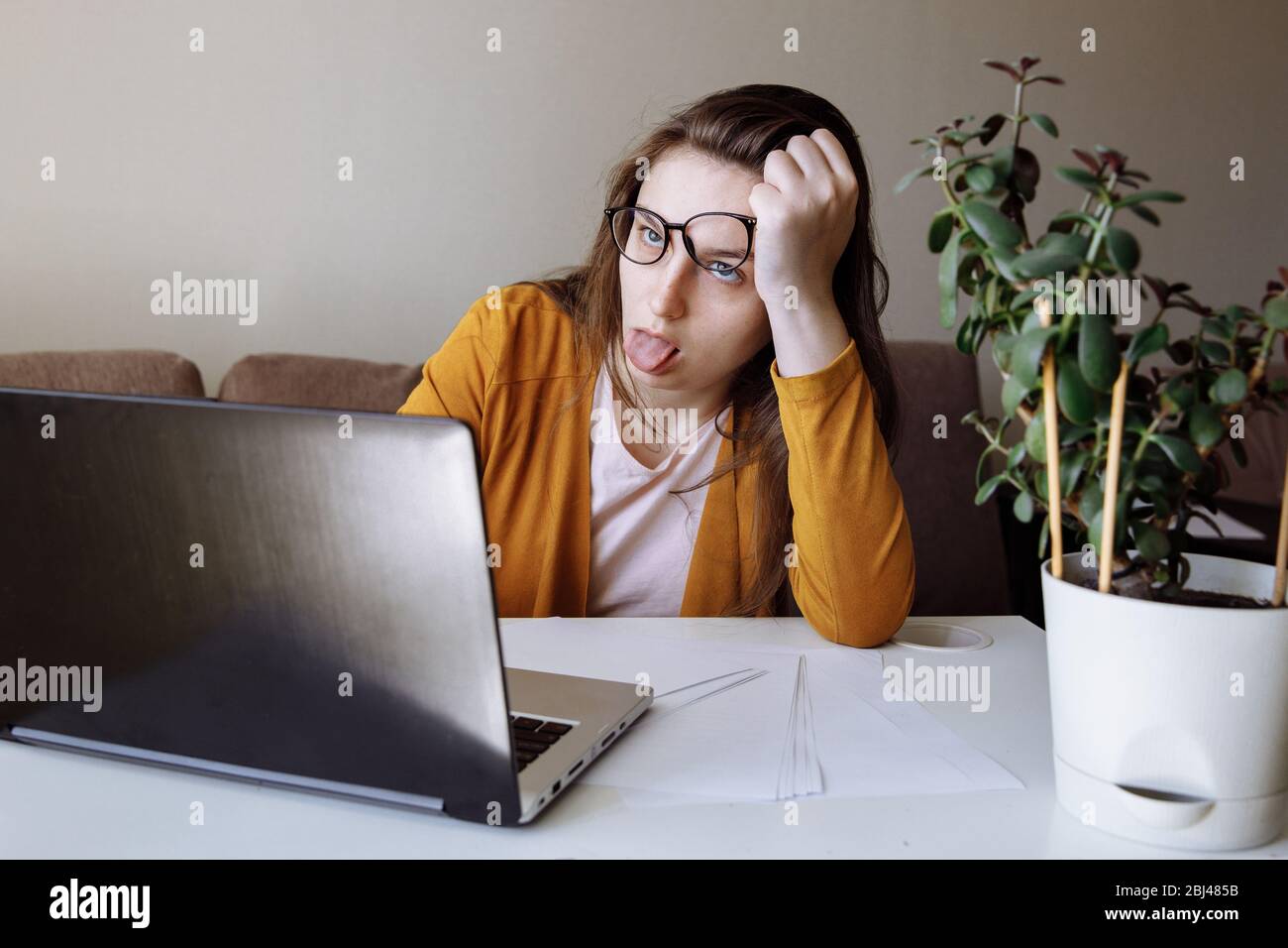 Difficoltà di comunicazione virtuale dall'ufficio domestico. La ragazza è seduta di fronte a un notebook. Foto Stock