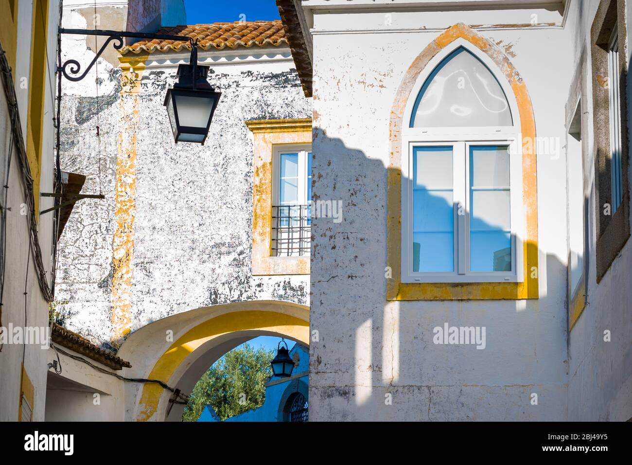 Case e palazzi tipici bianchi e gialli e lanterna a Evora, Portogallo Foto Stock