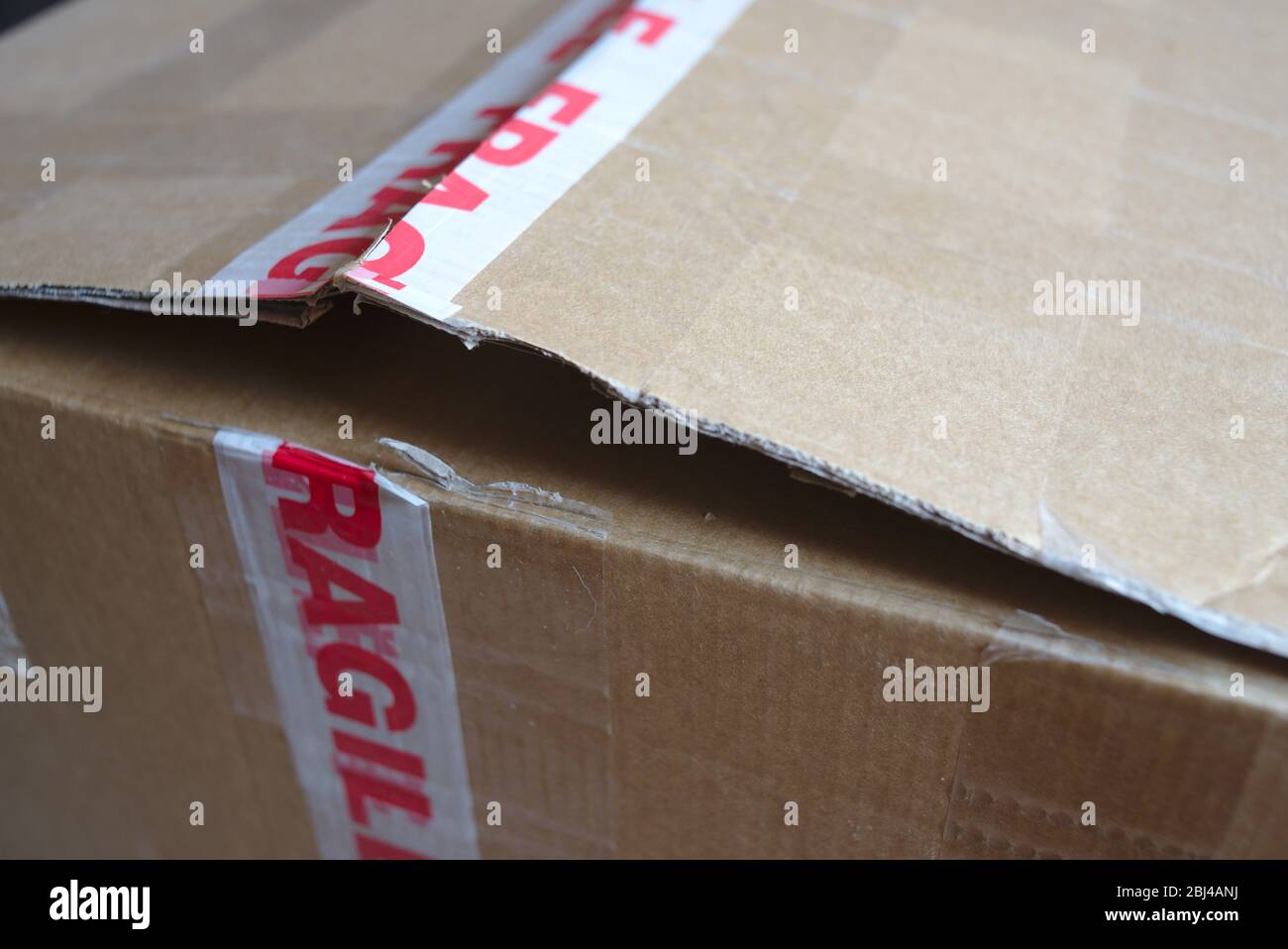 Confezione di cartone con nastro di avvertenza fragile. Foto Stock