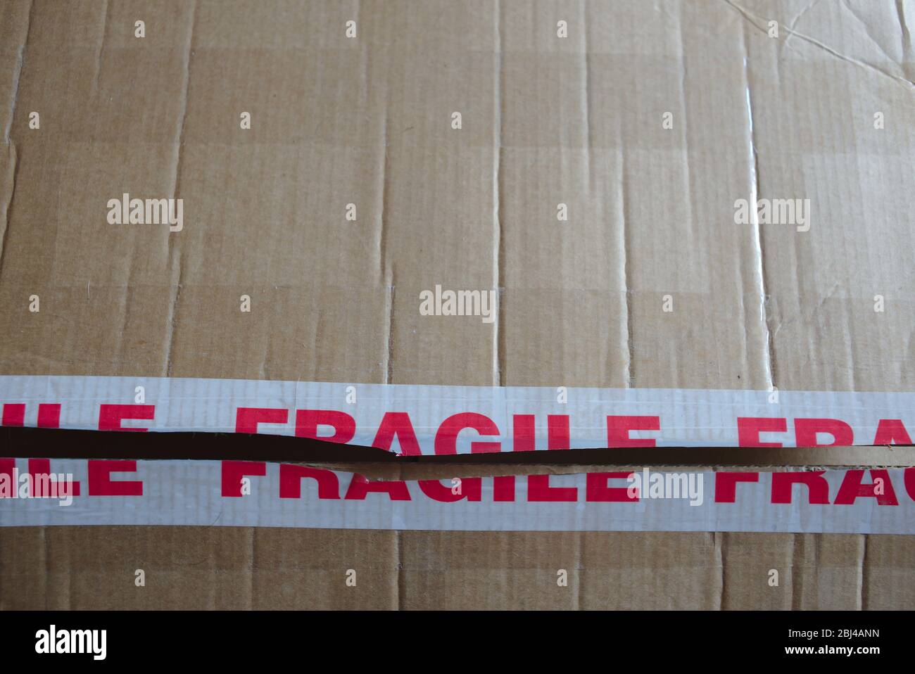 Confezione di cartone con nastro di avvertenza fragile. Foto Stock