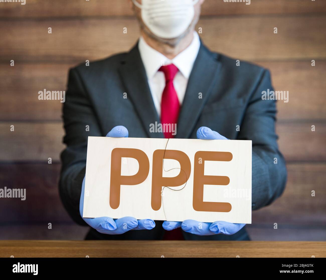 Un concetto di PPE di un uomo d'affari, medico o datore di lavoro che indossa guanti blu, chirurgici e maschera facciale e piecing insieme un puzzle puzzle con le lettere P. Foto Stock