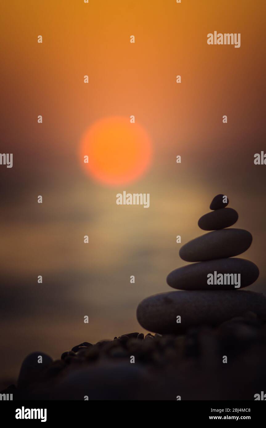 Piramide piegata Zen pietre ghiaia sul mare spiaggia al tramonto Foto Stock