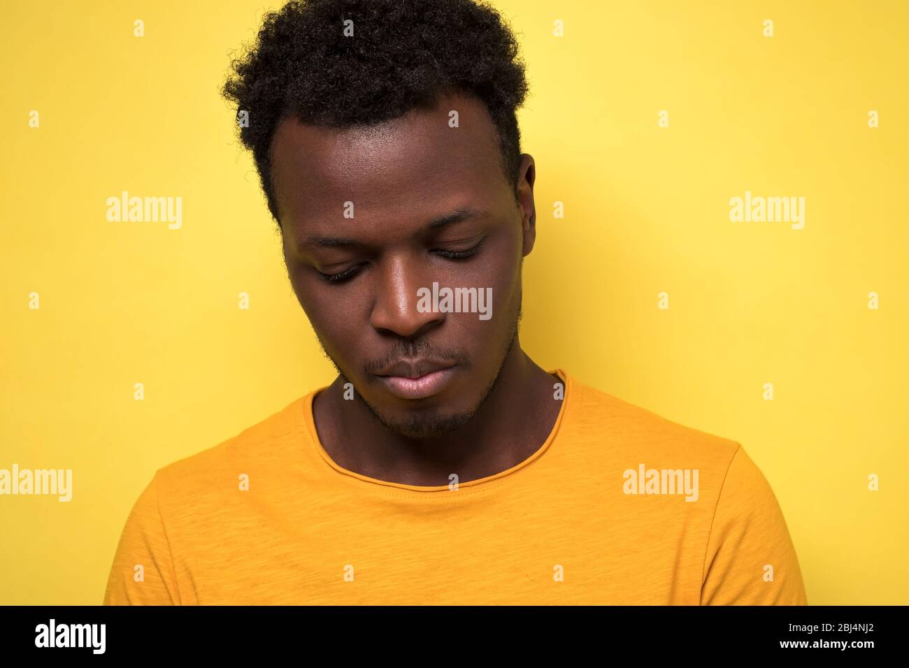Giovane afroamericano guardando giù con colpevole espressione confusa Foto Stock