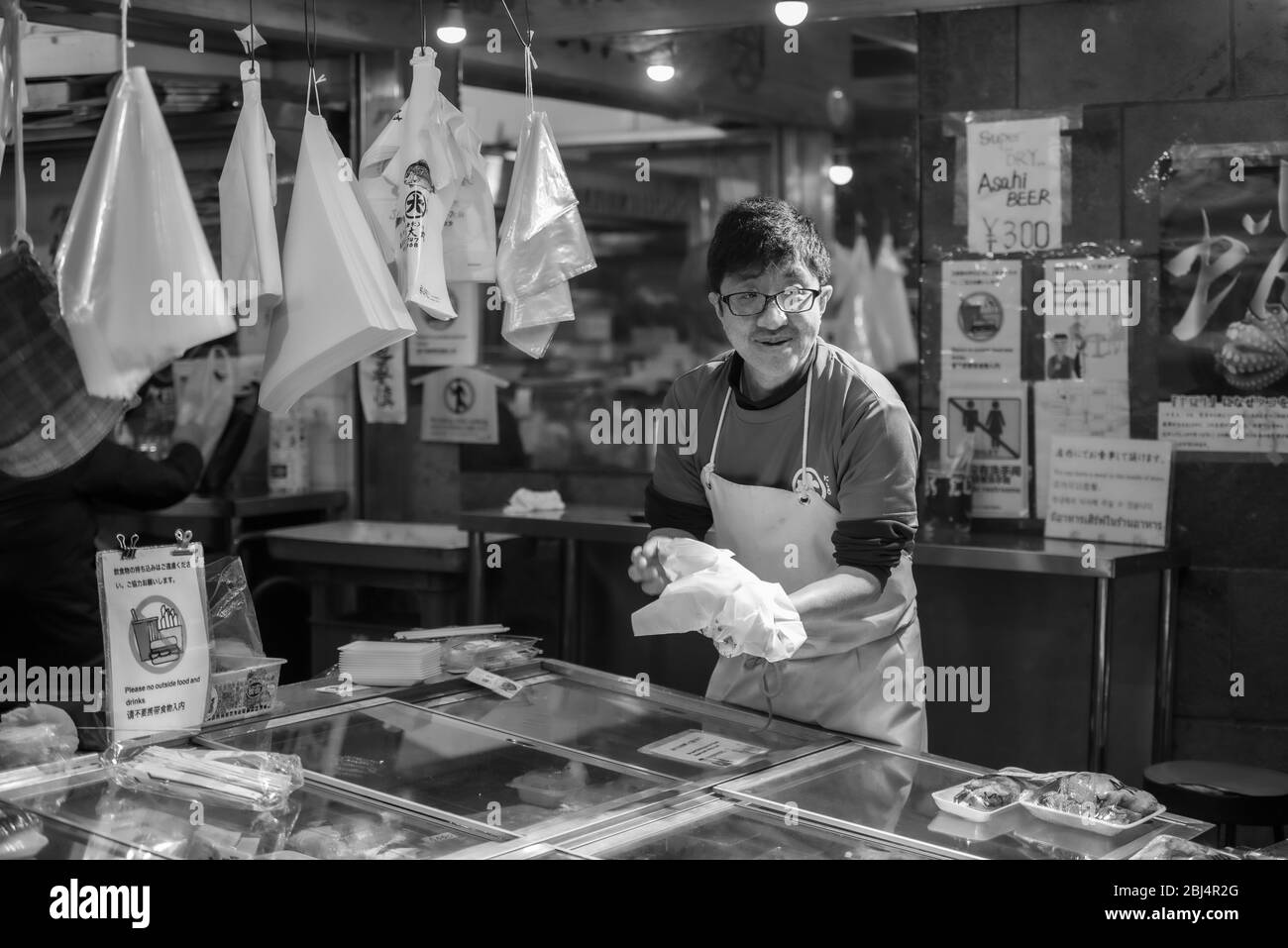 Un venditore al mercato alimentare Nishiki a Kyoto Giappone che offre e prepara cibo per la vendita. Foto Stock