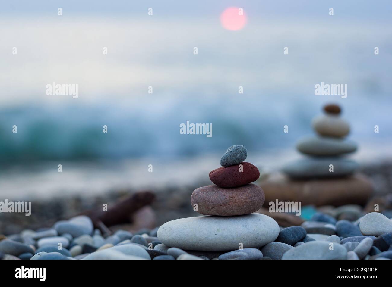 Piramide piegata Zen pietre ghiaia sul mare spiaggia al tramonto Foto Stock