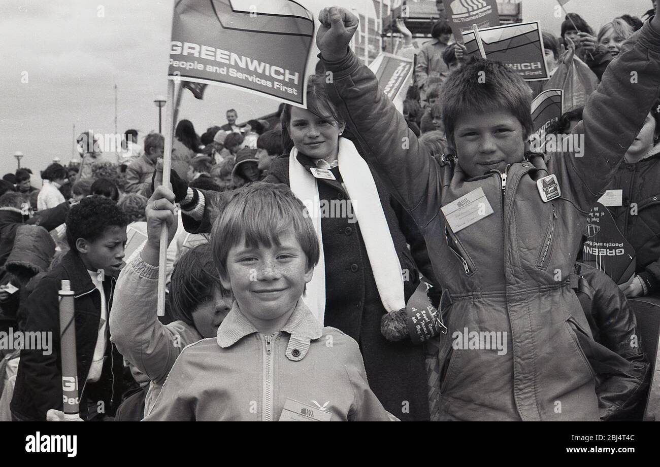 1984, 8 maggio, giovani storici ed eccitati fuori sventolando bandiere in attesa della comparsa di sua Maestà la Regina a Greenwich per l'apertura ufficiale del Thames Barrier, Charlton riverside, Greenwich, Londra, Inghilterra, Regno Unito. Foto Stock