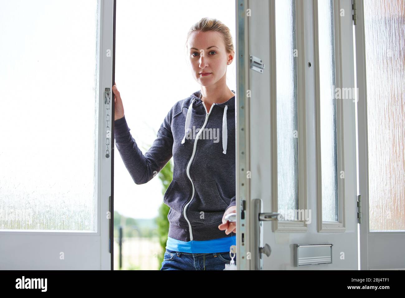 Scatto di una giovane donna che apre la porta d'ingresso ed entra in casa sua Foto Stock