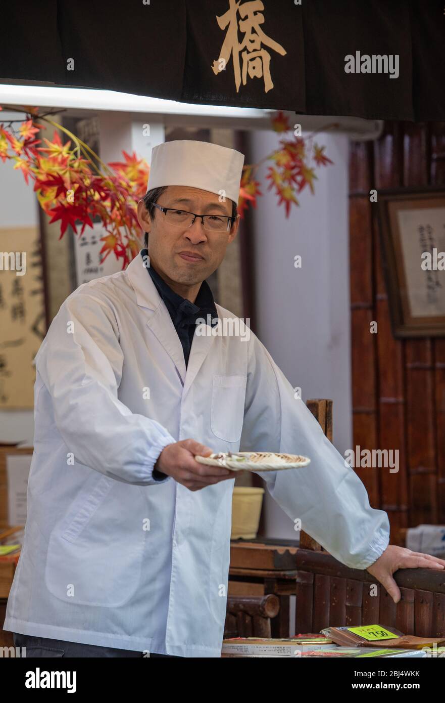 Uno chef offre assaggi di vari biscotti e gnocchi di tè ai turisti e ai visitatori in via Matsubara Dori a Kyoto Giappone. Foto Stock