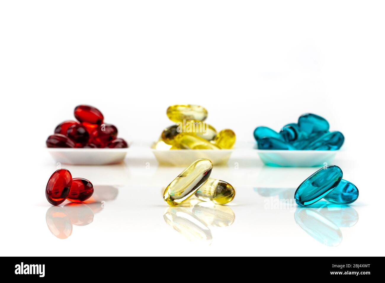 Una miscela di capsule di gel morbido medico multicolore su sfondo bianco - integratori medici , rosso, giallo, blu Foto Stock
