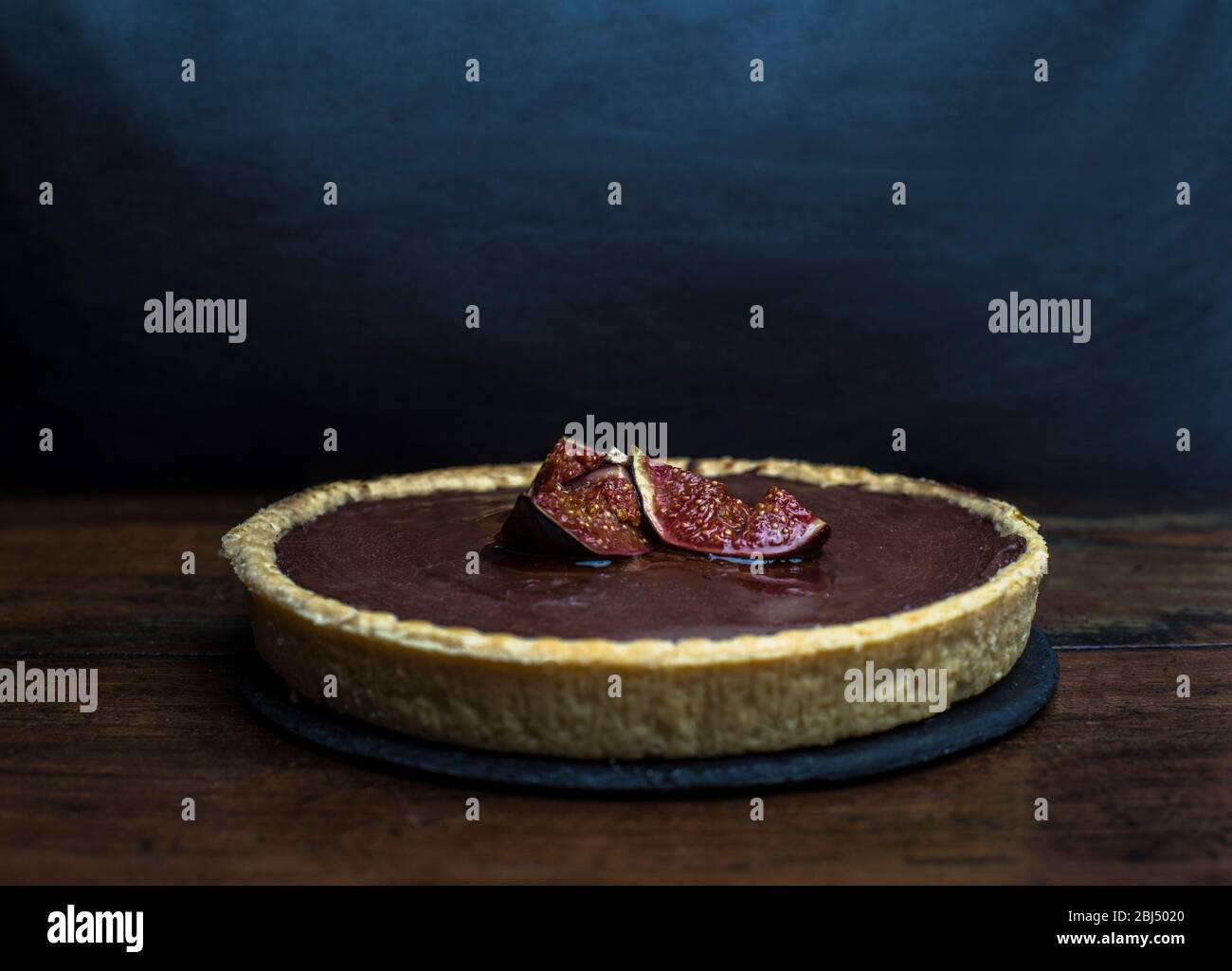 Una crostata di cioccolato e fichi su sfondo blu. Foto Stock