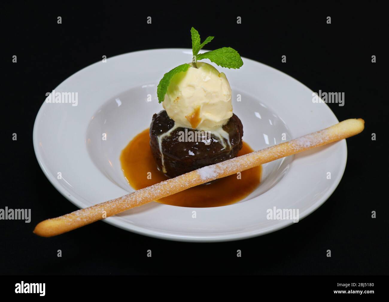 Sticky toffee pudding con gelato alla vaniglia e salsa di caramello Foto Stock