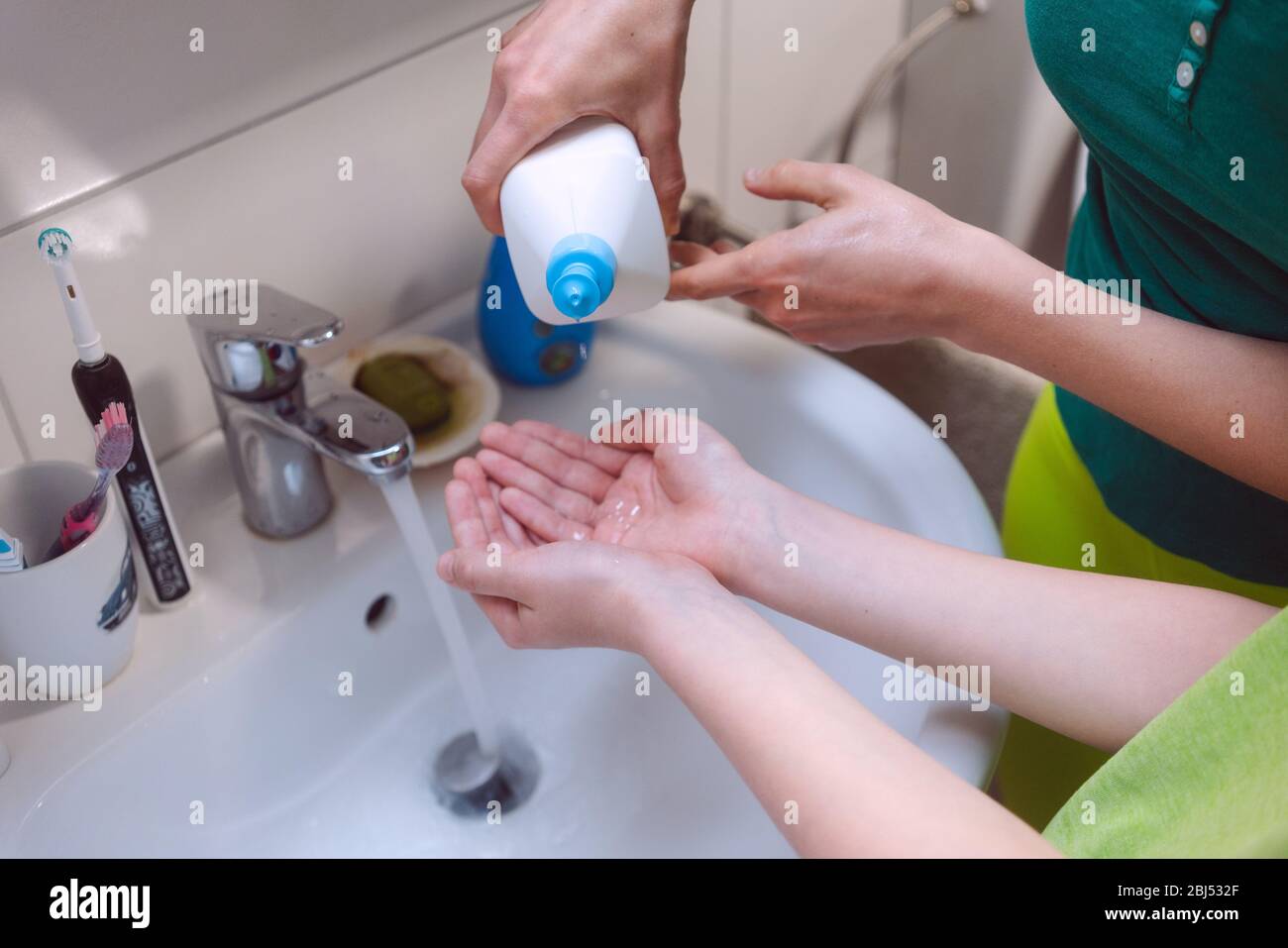 Madre disinfettante le mani dei figli Foto Stock