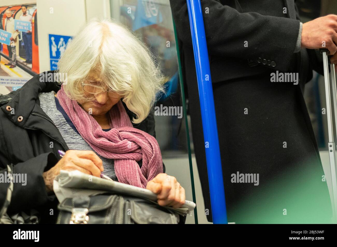 Ritratto di una donna anziana che fa una parola chiave sulla metropolitana di Londra, Inghilterra Foto Stock