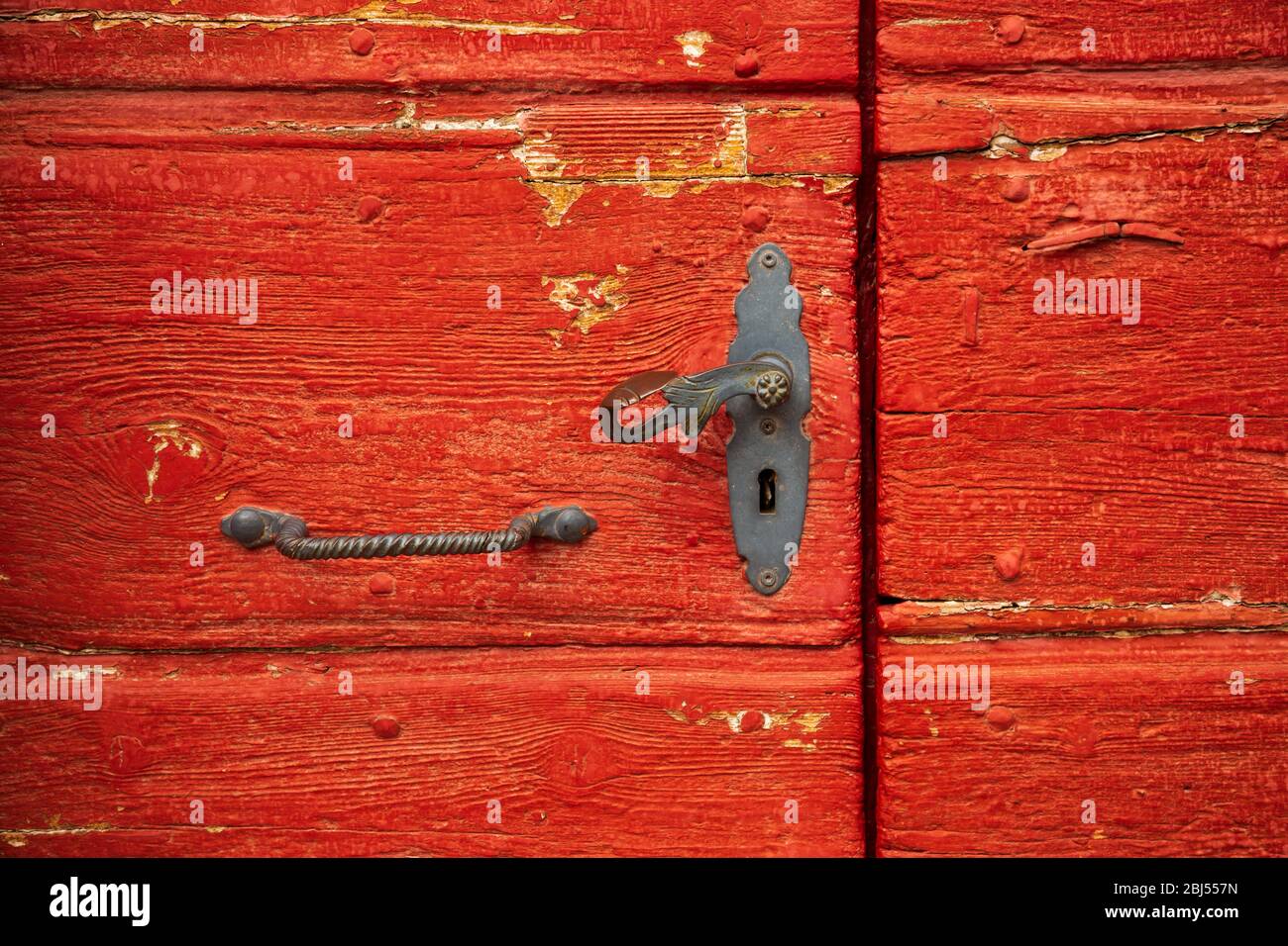 Porta in legno rosso vintage con manico in ferro vecchio Foto Stock