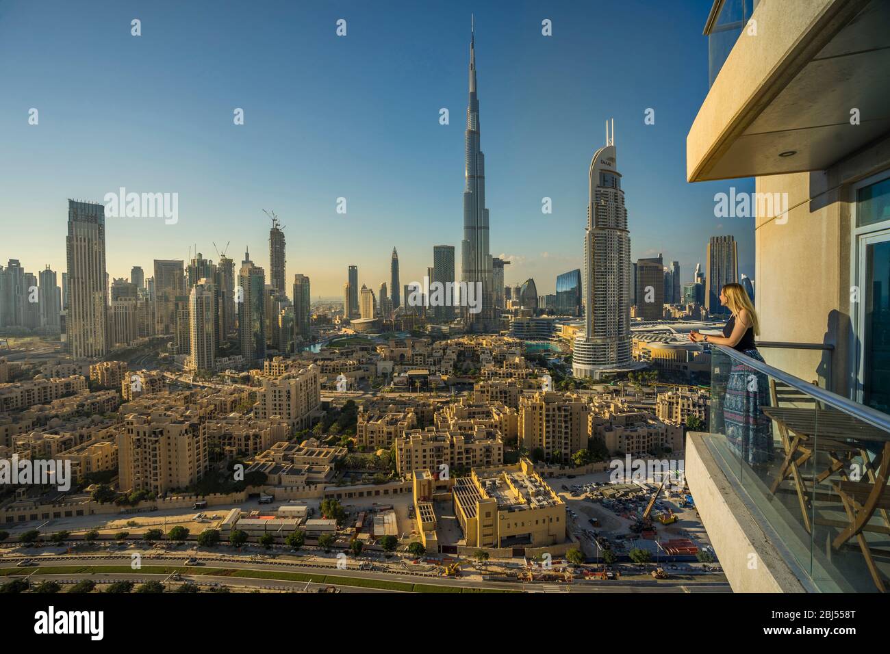 Una donna si trova al di fuori del balcone del suo appartamento a Dubai. Foto Stock