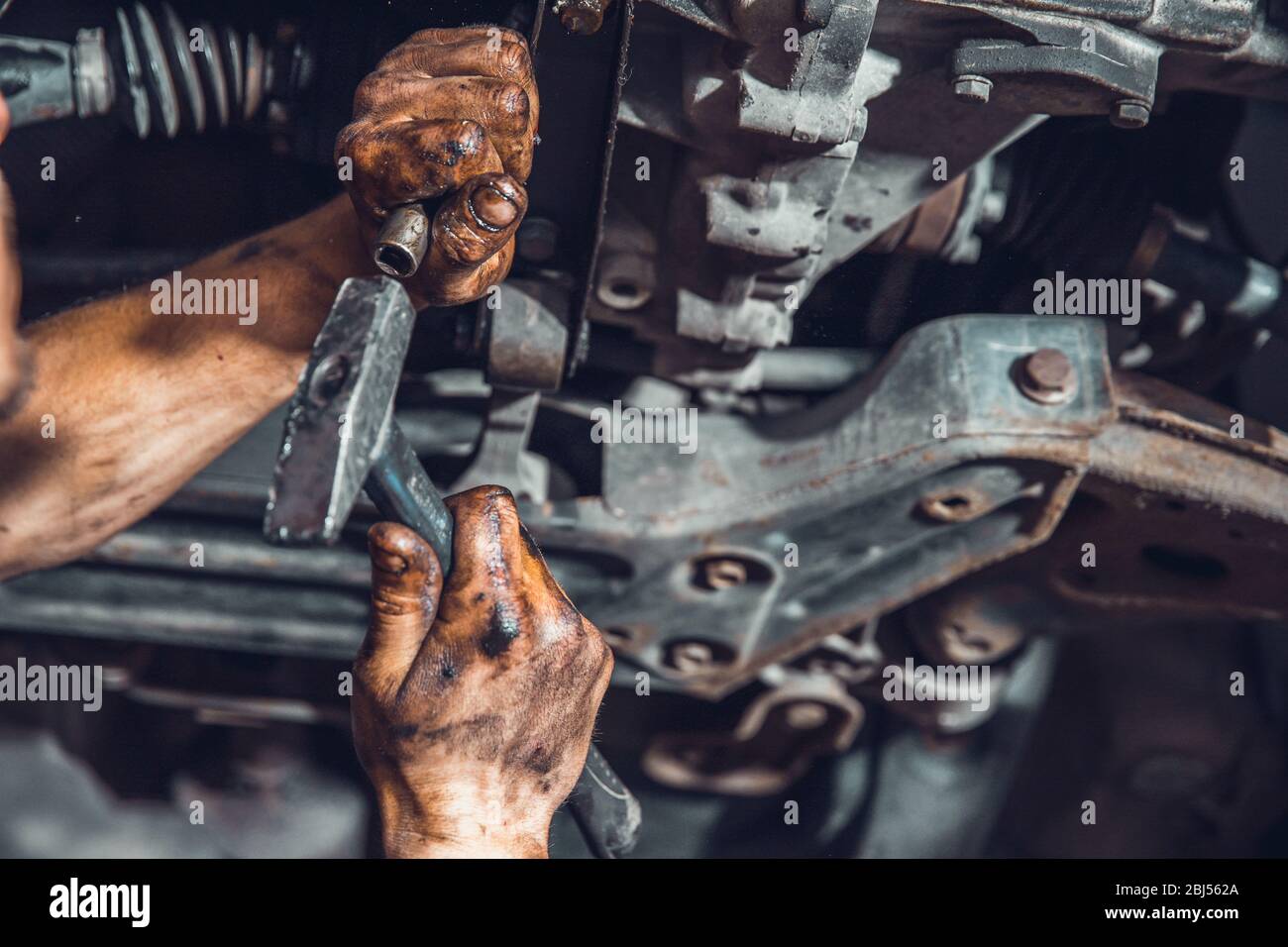 allentare la vite sulla vettura durante la riparazione durante la manutenzione con l'aiuto del regolatore e del martello Foto Stock