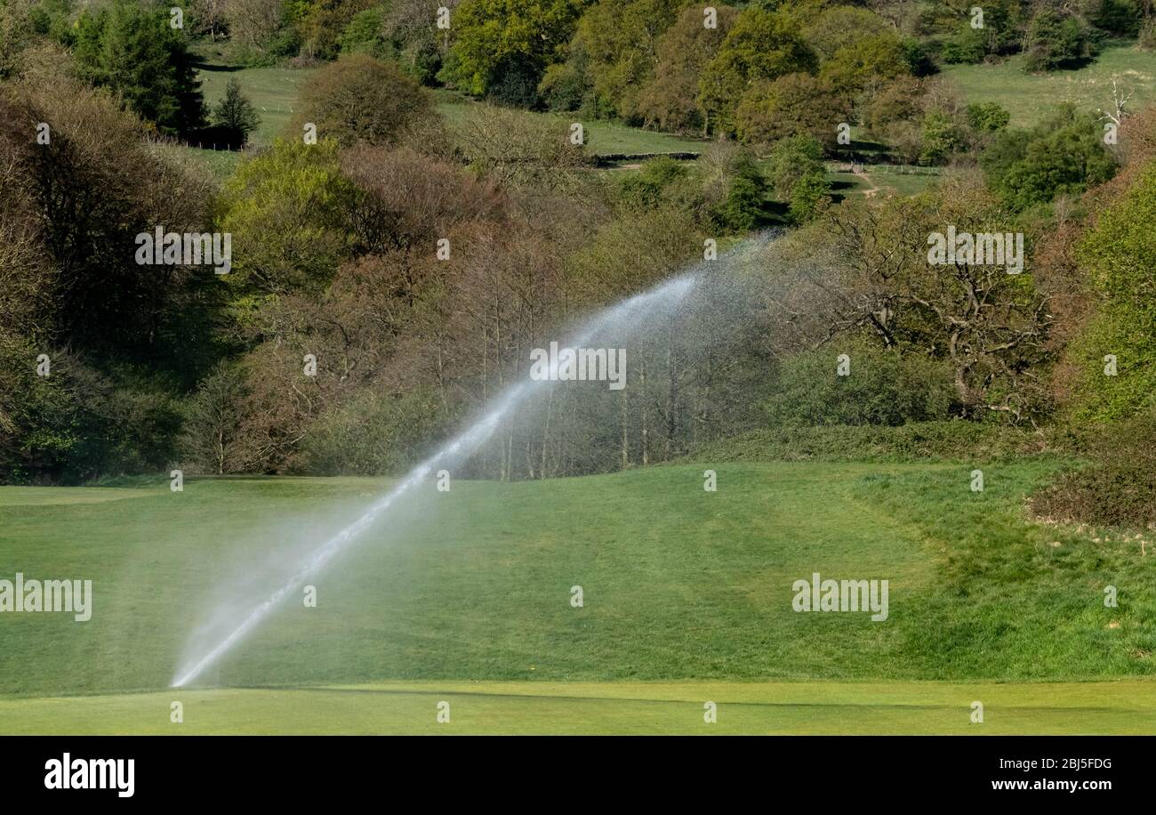 Un sistema di irrigazione che innaffia un campo da golf. Foto Stock