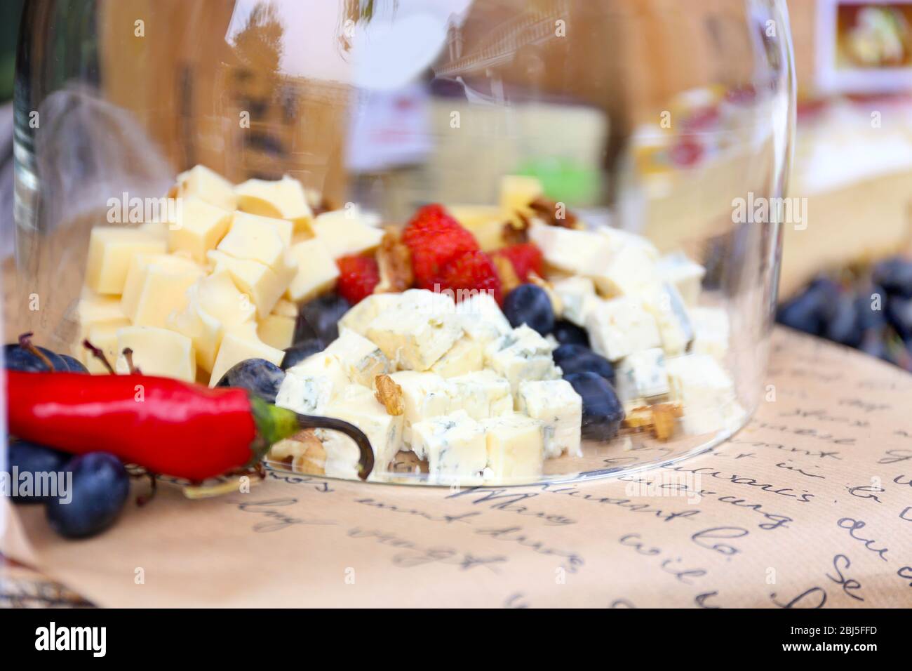 Formaggio e frutti di bosco sotto la ciotola di vetro sul tavolo Foto Stock