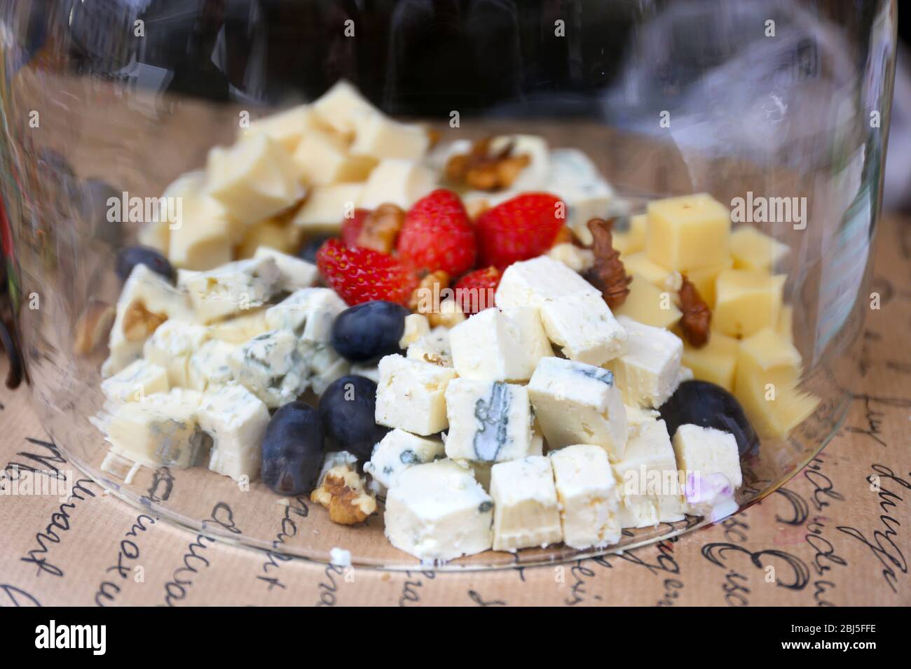 Formaggio e frutti di bosco sotto la ciotola di vetro sul tavolo Foto Stock