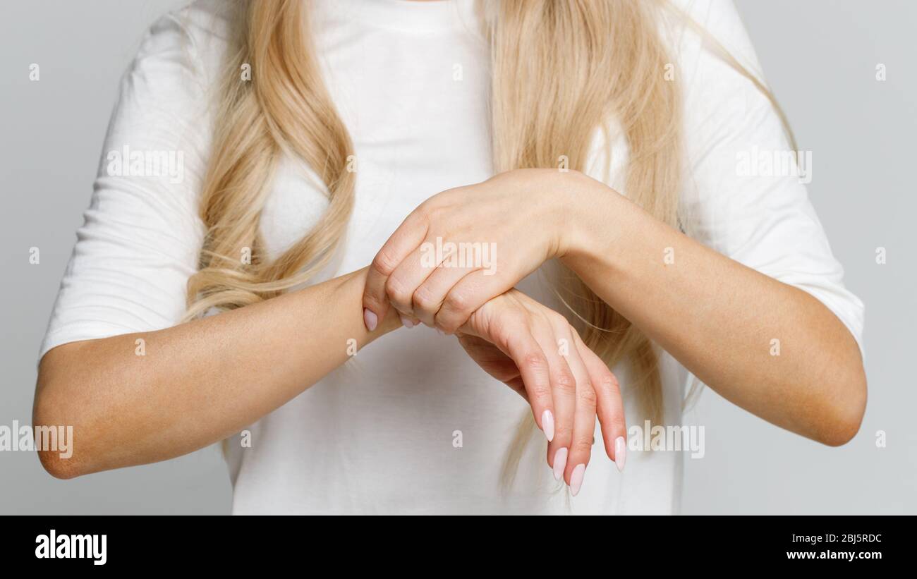 Primo piano delle braccia della donna che tiene il suo polso doloroso causato da un lavoro prolungato sul computer, laptop. Sindrome del tunnel carpale, artrite, disordine neurologico Foto Stock