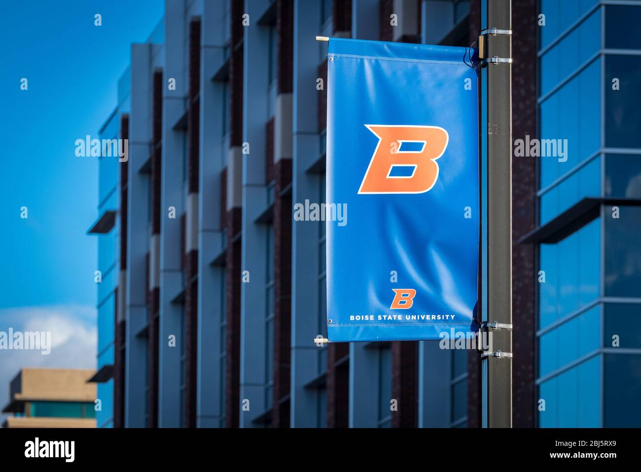 Bandiera del logo della Boise state University "B" davanti agli edifici del campus e ai cieli blu. Foto Stock