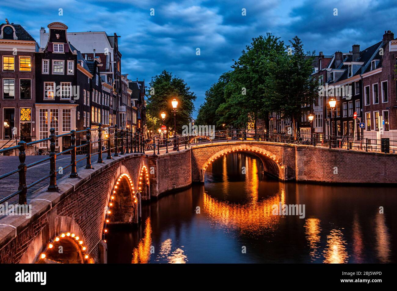 Amsterdam, Paesi Bassi. Sette ponti. Canali Keizersgracht e Reguliersgracht, illuminati con le piccole luci che si riflettono sul fiume Foto Stock