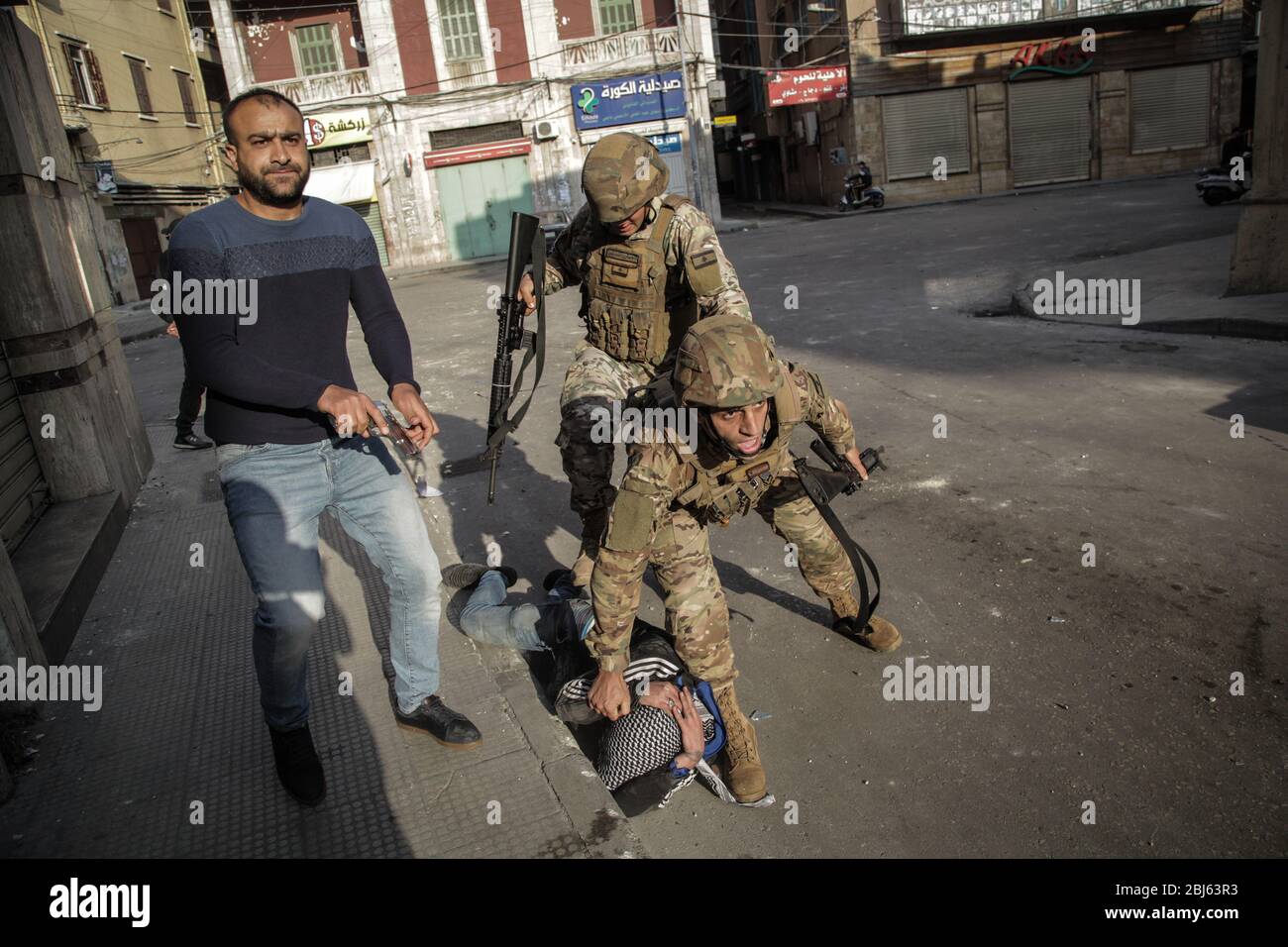 Tripoli, Libano, 28 aprile 2020. Un uomo con una pistola a mano si erge mentre i soldati abbattono violentemente un protesta durante i disordini scoppiati dopo la morte di un uomo ucciso dall'esercito durante le proteste innescate dal collasso economico la notte precedente. Elizabeth Fitt Credit: Elizabeth Fitt/Alamy Live News Foto Stock