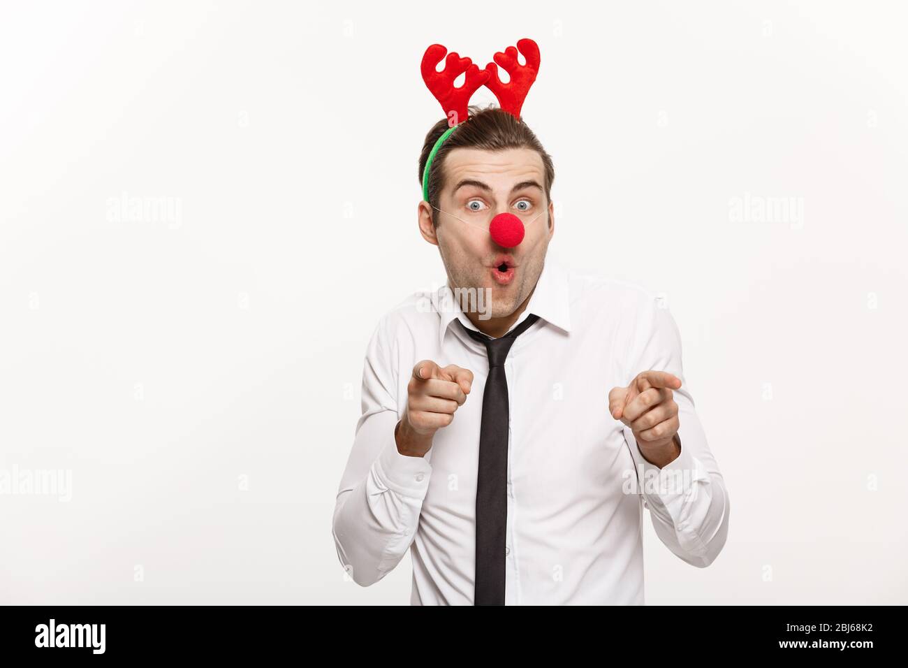 Concetto di Natale - bell'uomo d'affari che indossa la fascia di renna facendo l'espressione facciale divertente. Foto Stock