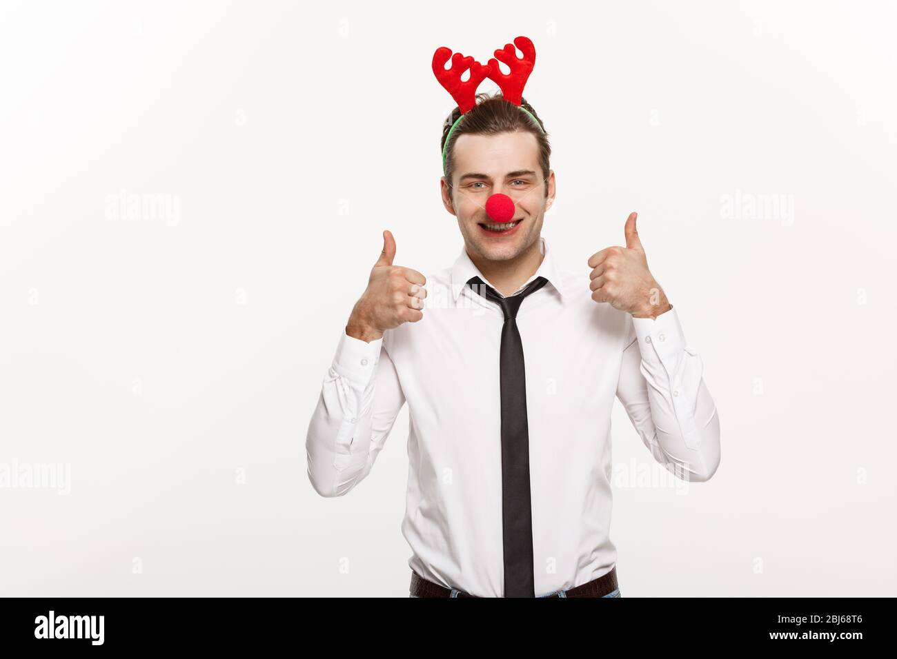 Concetto di Natale - bell'uomo d'affari che indossa la fascia di renna facendo l'espressione facciale divertente. Foto Stock