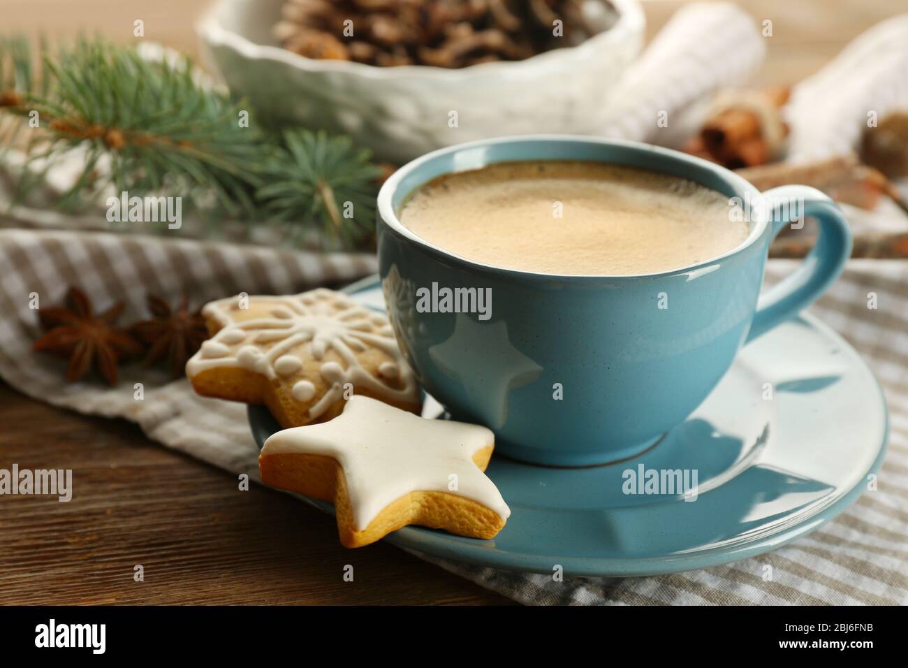 Tazza di caffè con biscotti a forma di stella e rametto di albero di Natale su tovagliolo Foto Stock