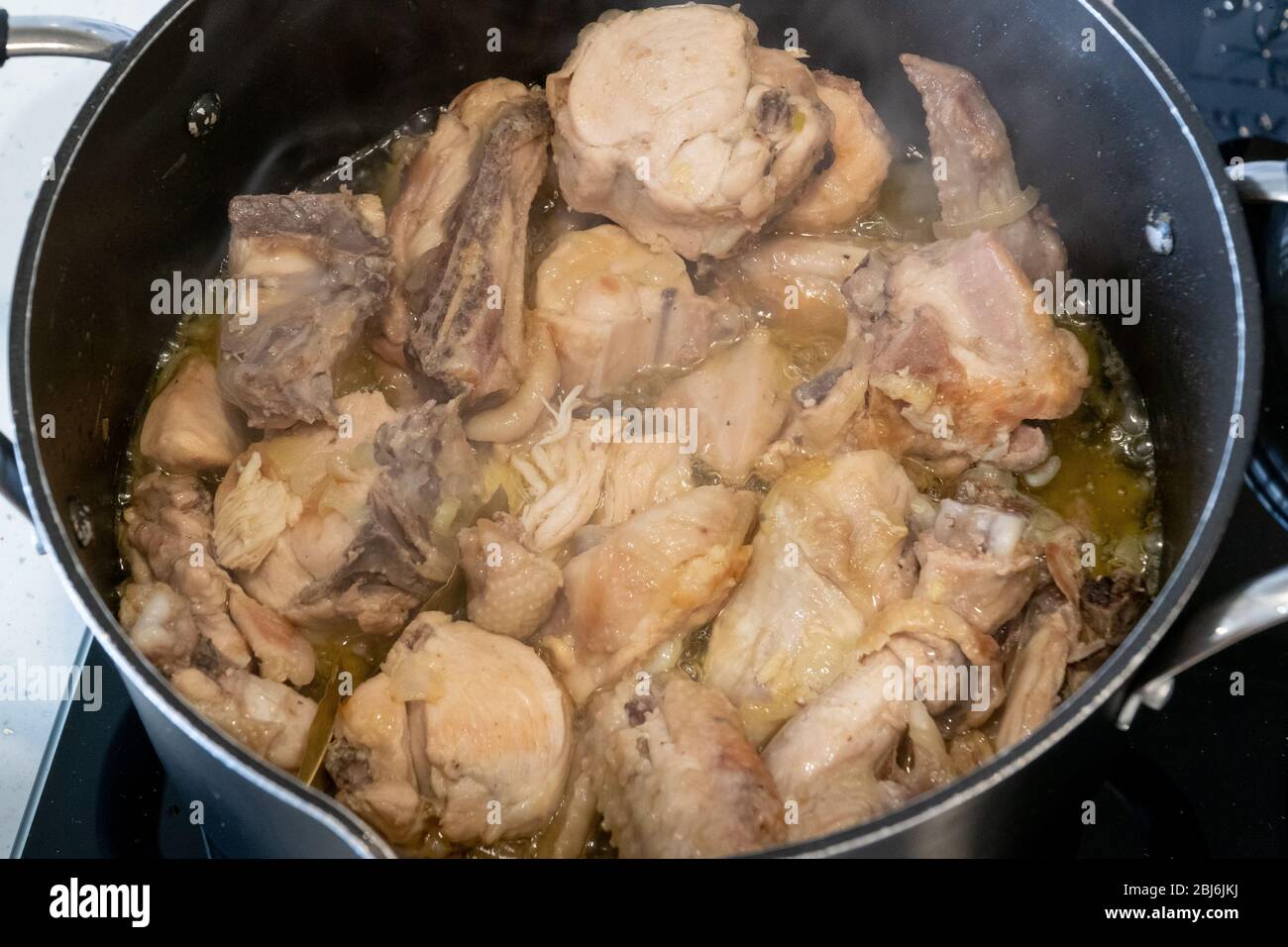 Carne di pollo stufato in una padella. Carne rustica fatta in casa. Vista dall'alto con fumo. Cuoco a casa. Foto Stock