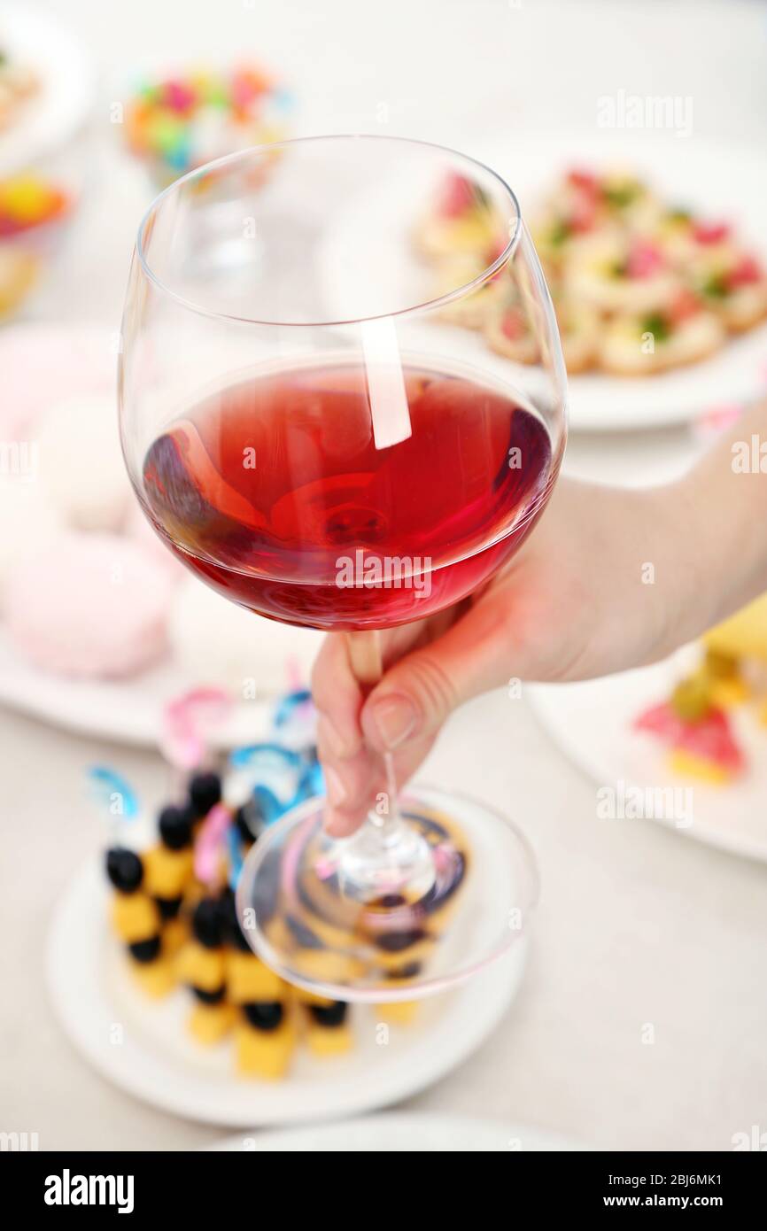 Donna che tiene il wineglass su sfondo del buffet Foto Stock