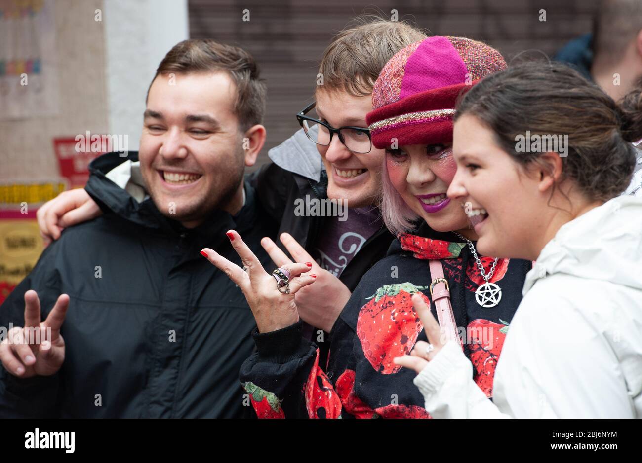 Un teen giapponese che indossa abiti contemporanei e un cappello in posa per le foto con i turisti in Takeshita Street, il centro di moda di Harajuku a Tokyo Foto Stock